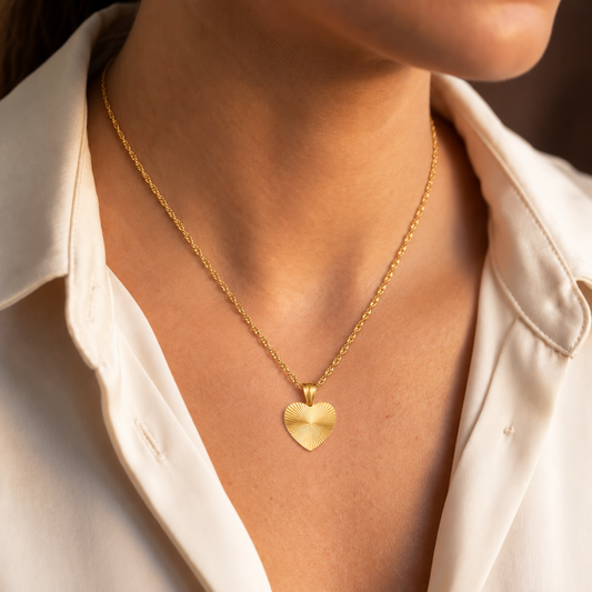 Woman wearing a small gold heart necklace with a white shirt