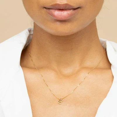 Woman wearing a gold initial necklace on a fine box chain