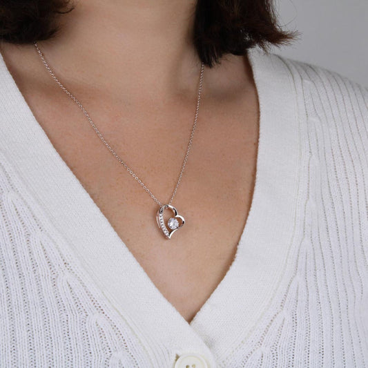 Woman wearing a heart necklace with a white cardigan